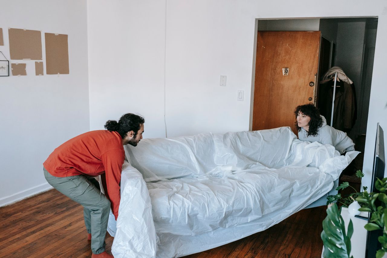 team-03 A couple collaboratively lifting a couch while moving into a new apartment.